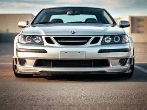 Srebrny Saab 9-3 z dyskretnym sportowym body kit, obniżonym zawieszeniem i dopasowanymi zderzakami na miejskim parkingu